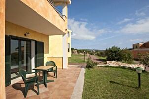 A patio with a table and chairs, a stone wall, and a view of the countryside.