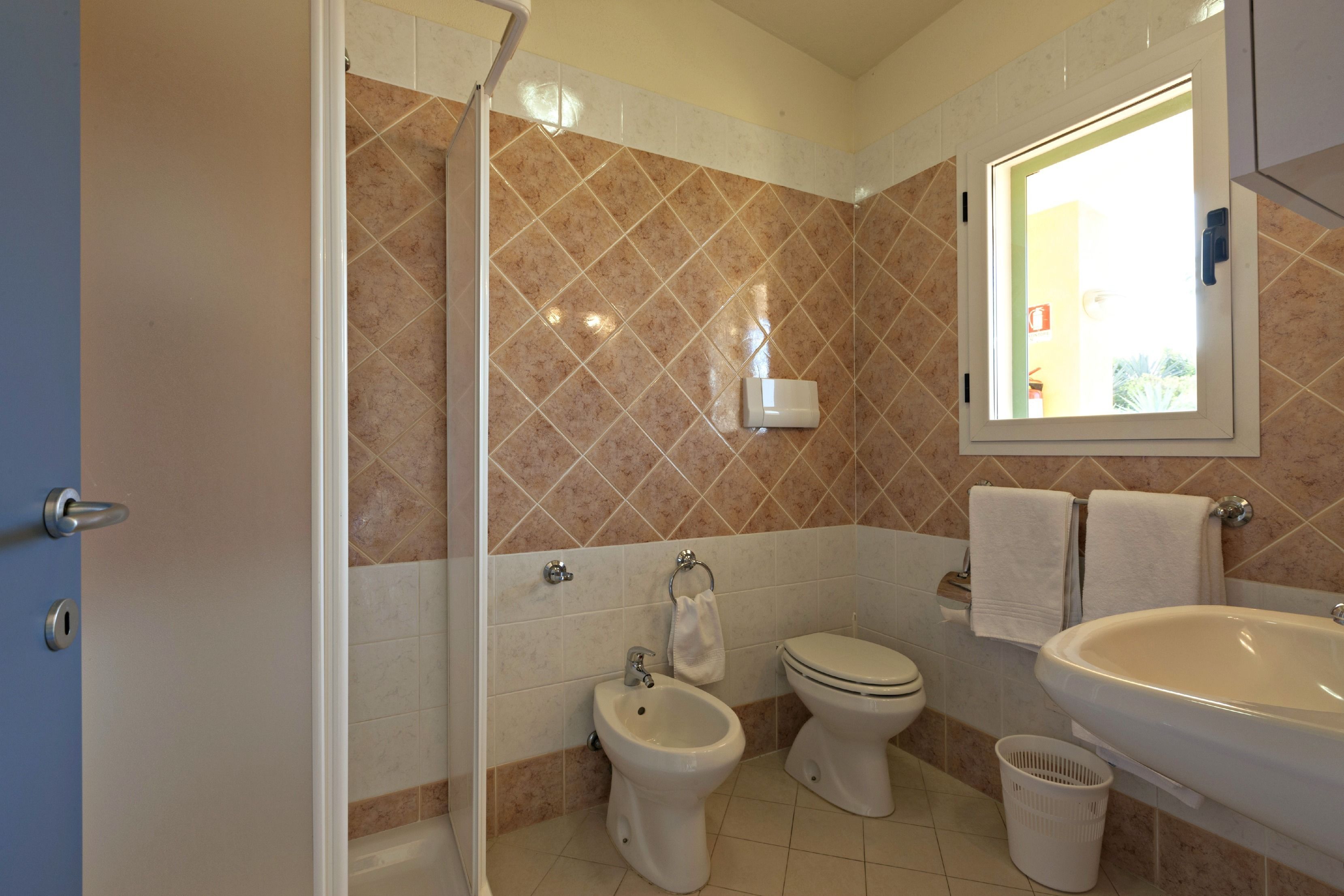 Een badkamer met douche, toilet, wastafel en bidet.