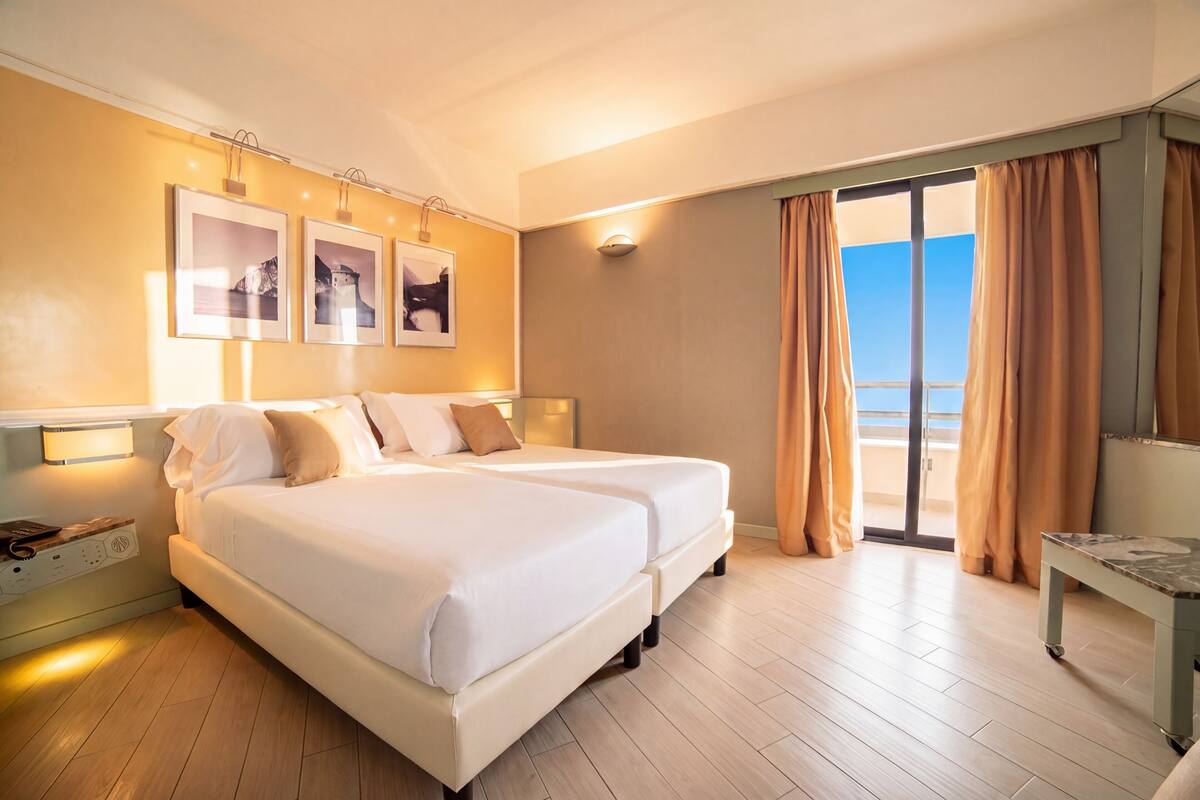 Une chambre d’hôtel avec un lit, un bureau et une vue sur la plage.