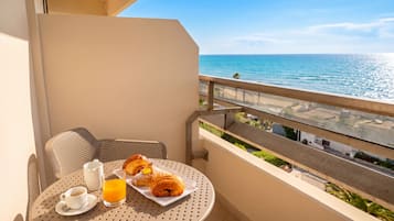 Un balcón con una mesa lista para el desayuno, con vista al mar.
