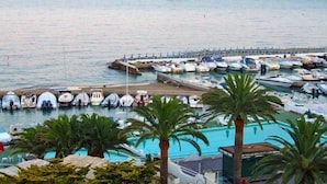 Marina con numerosos barcos amarrados, piscina y palmeras.