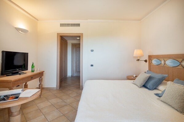 Una habitación de hotel con una cama, televisión, escritorio y lámpara.