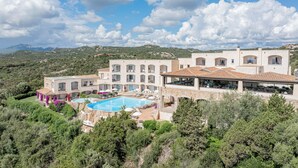 Un resort con piscina, varios balcones y montañas al fondo.