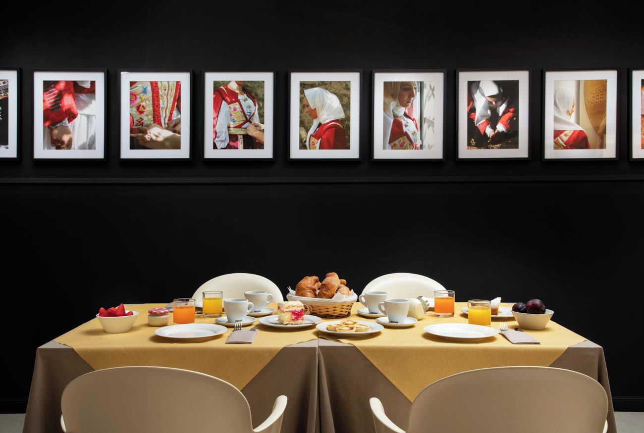 Een eettafel gedekt met ontbijtartikelen, omringd door ingelijste foto's aan de muur.