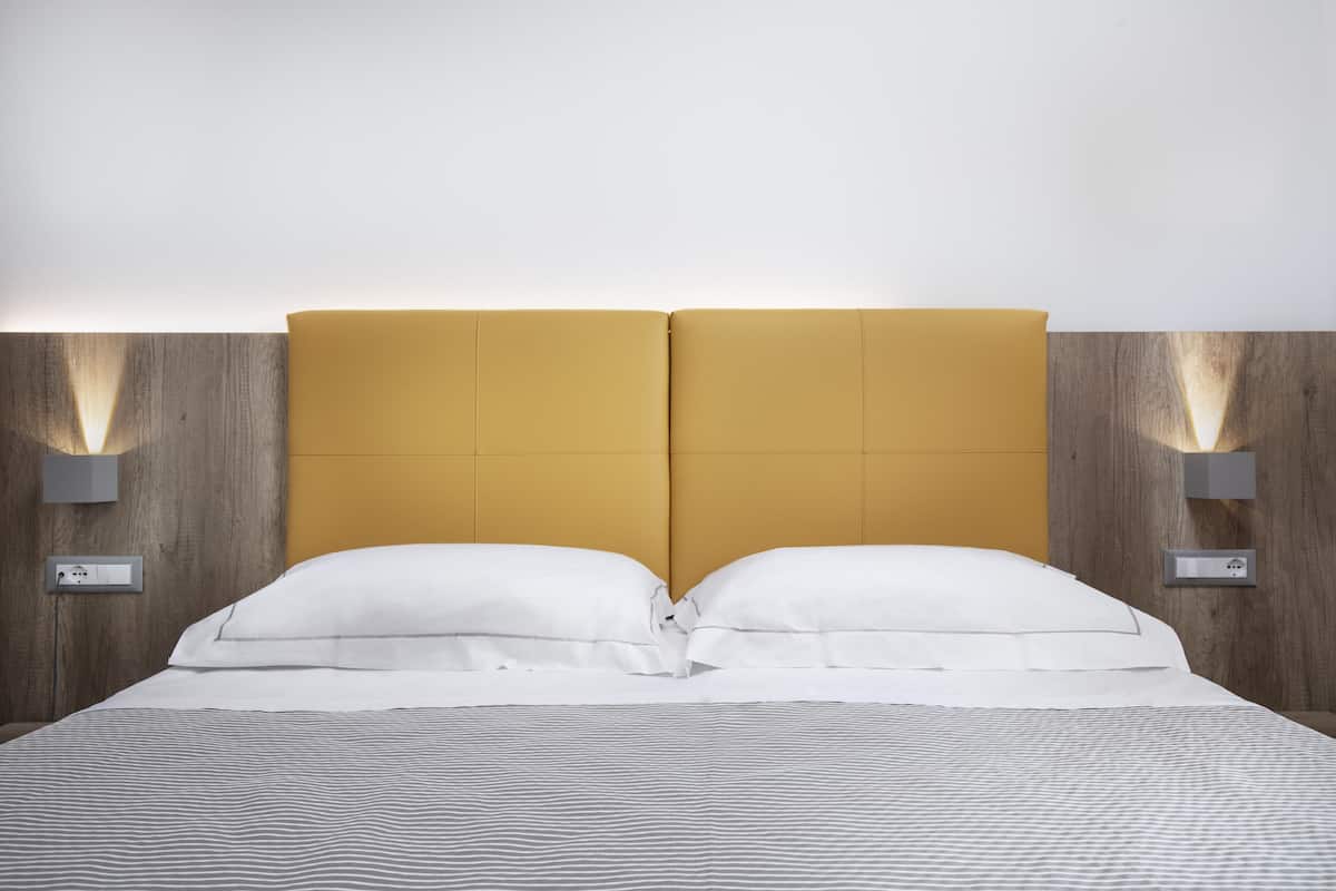 Ein Bett mit Holz-Kopfstütze, zwei Nachttischlampen und einer gestreiften Bettdecke.