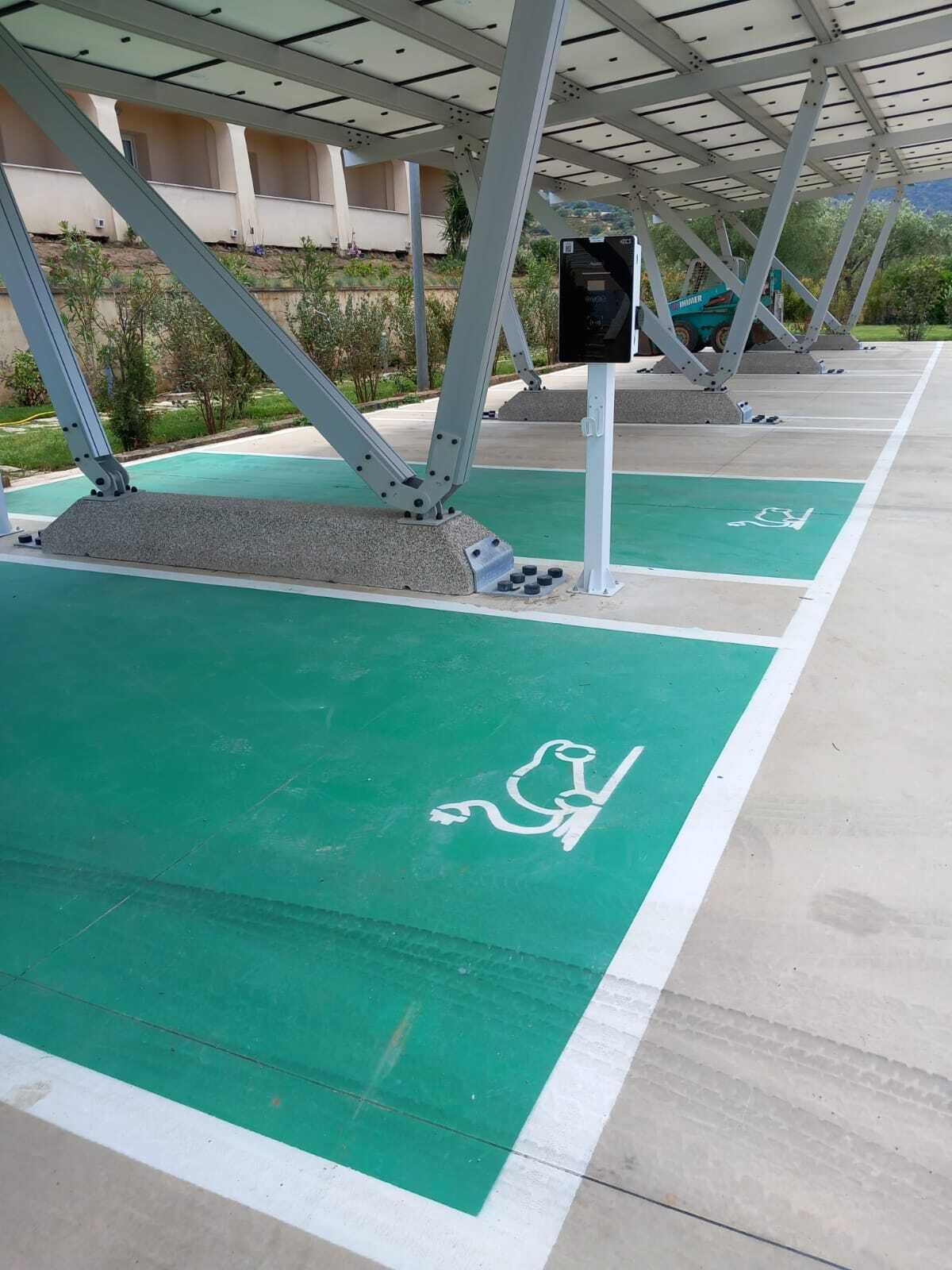 A parking area with green spaces marked for disabled parking, metal structural supports, and a concrete floor.