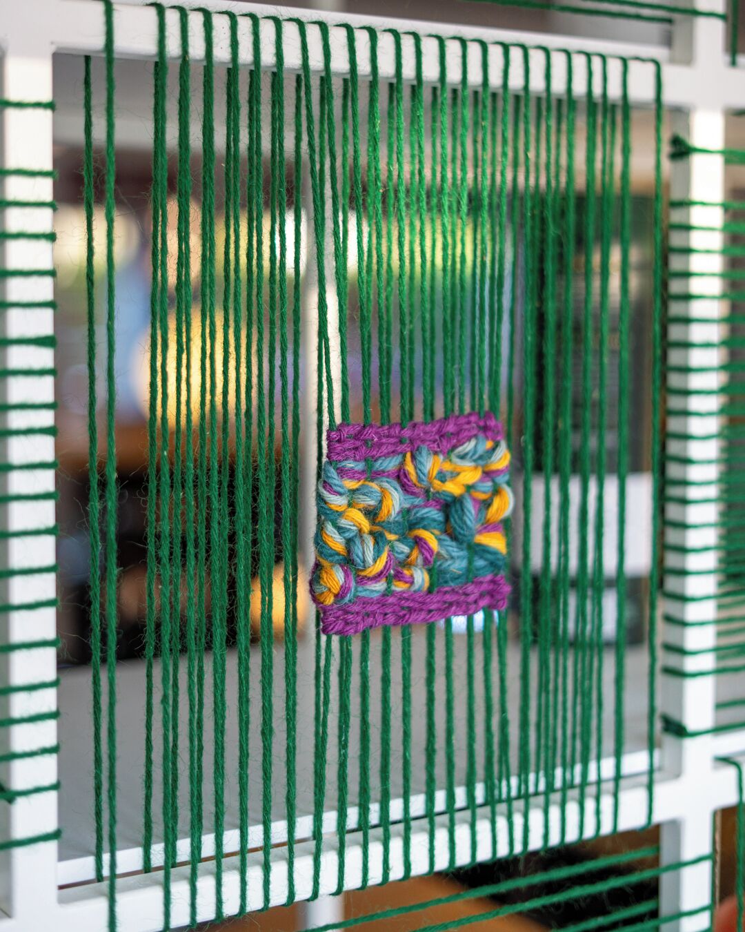 A close-up of a green woven textile with a colorful patch in the center.