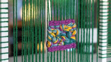 A close-up of a green woven textile with a colorful patch in the center.