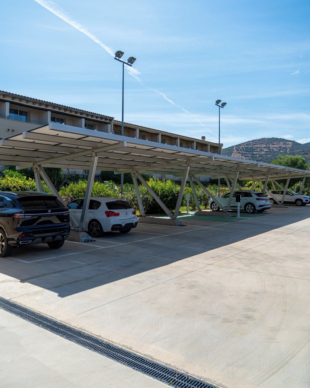 Een parkeerplaats met overdekte autoparkeerplaatsen en een gebouw op de achtergrond.