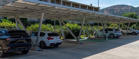 A parking area with covered carports and a building in the background.