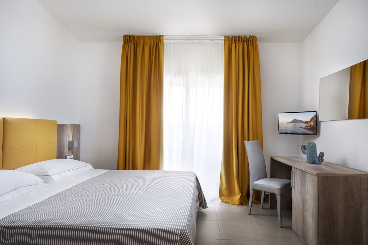 Ein Hotelzimmer mit Bett, Schreibtisch, Stuhl, Lampe und einem Bild an der Wand.