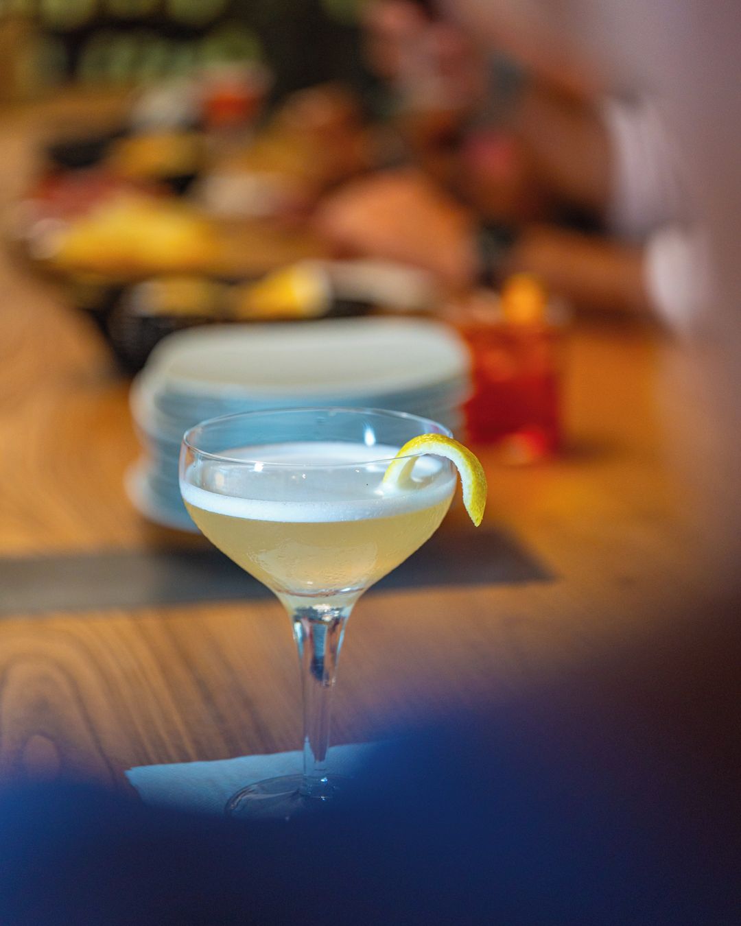 Ein Martini-Glas mit Zitronenzeste auf einer Holztischplatte.