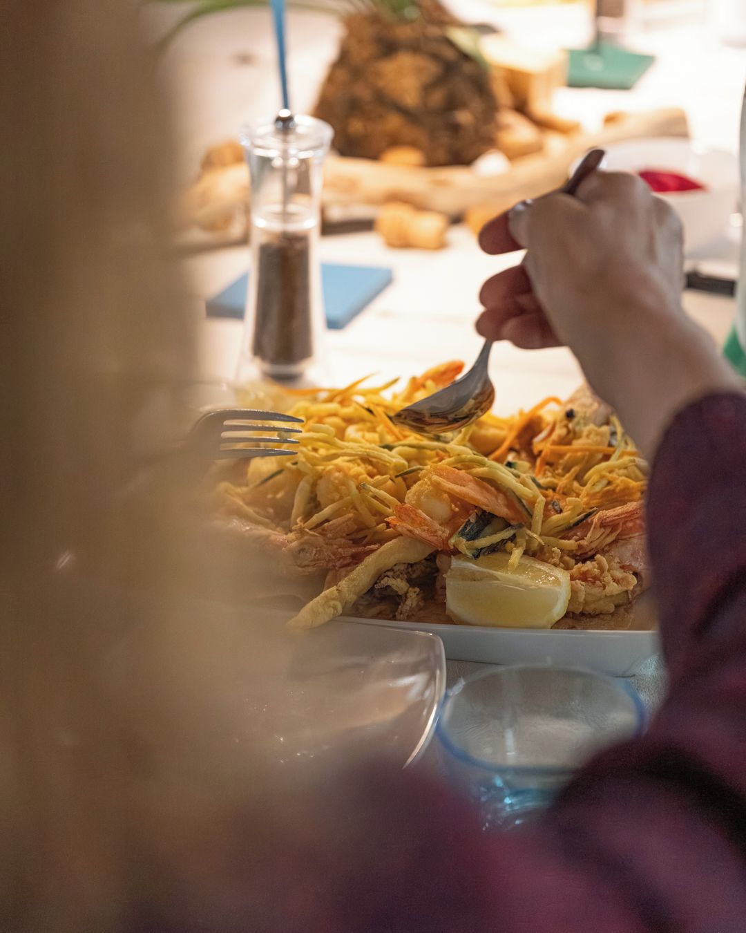 A dining table with a plate of food, a glass of water, and a salt shaker.