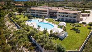 A large hotel with a swimming pool, multiple balconies, and a view of the surrounding landscape. - Hotel San Teodoro (San Teodoro)