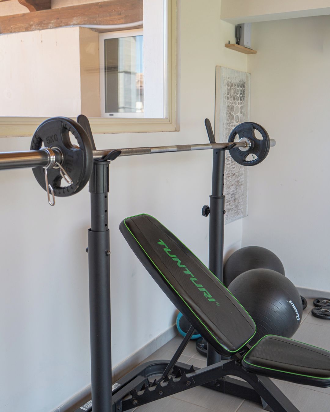 A home gym with a bench press, barbell, and weight plates.