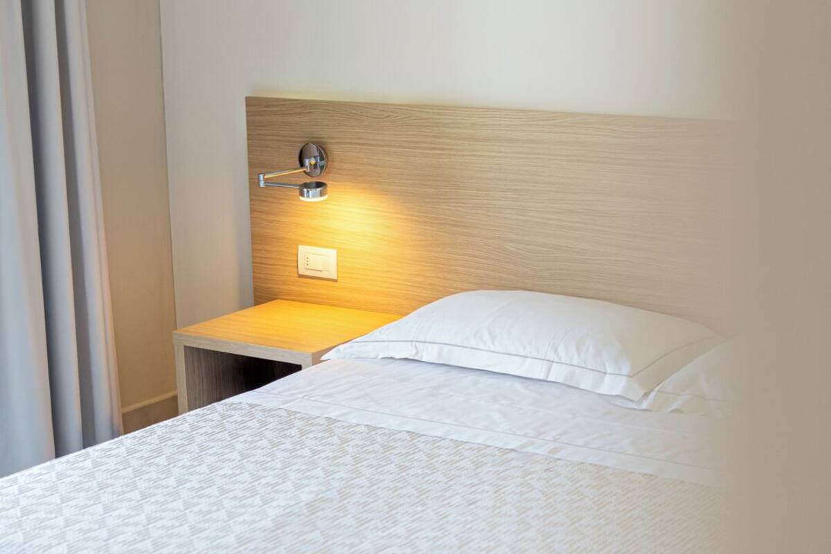 Ein Hotelzimmer mit Bett, Nachttisch und Wandlampe.