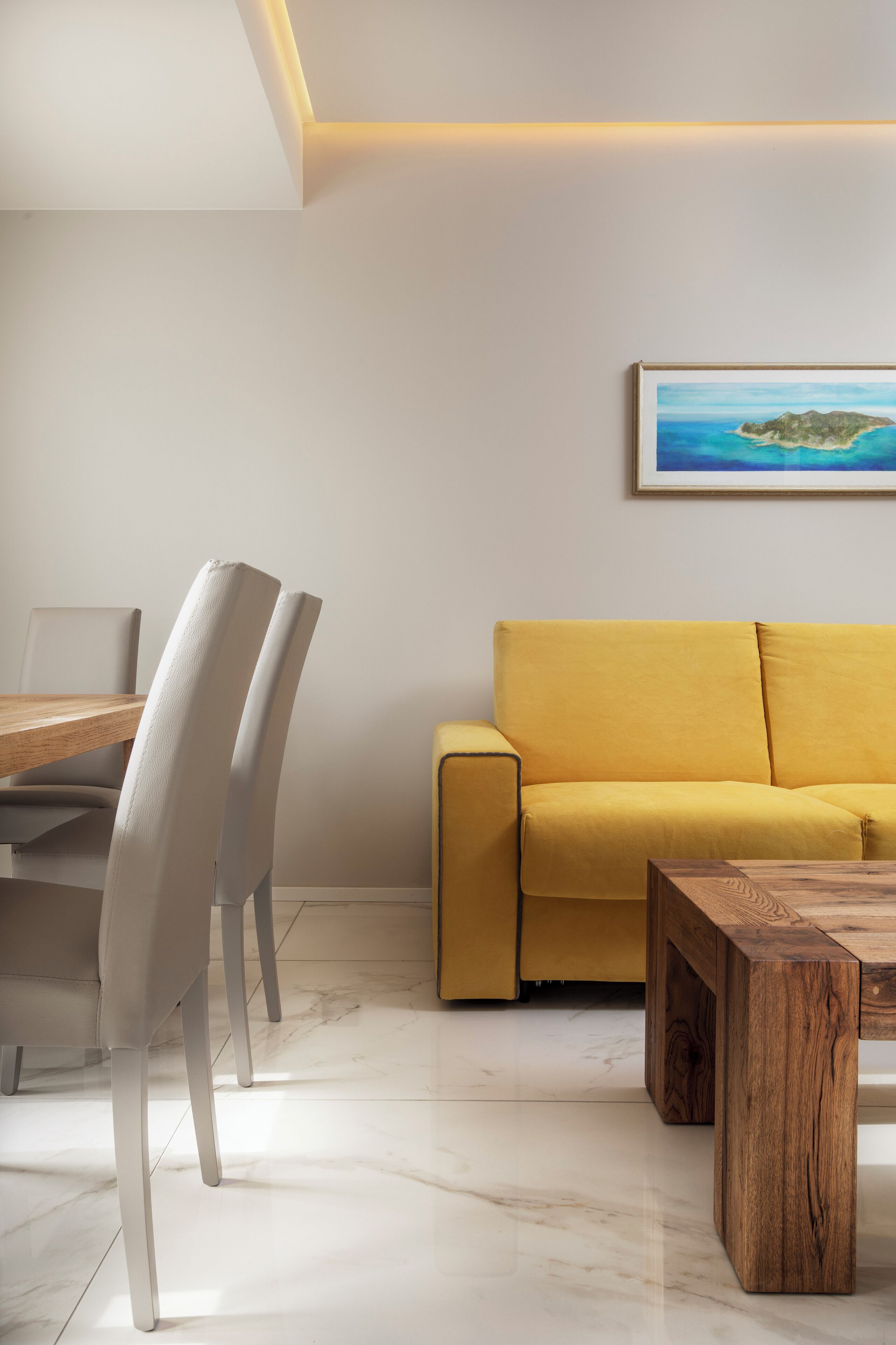 A modern living room with a wooden dining table, white chairs, a yellow sofa, and a wooden coffee table.