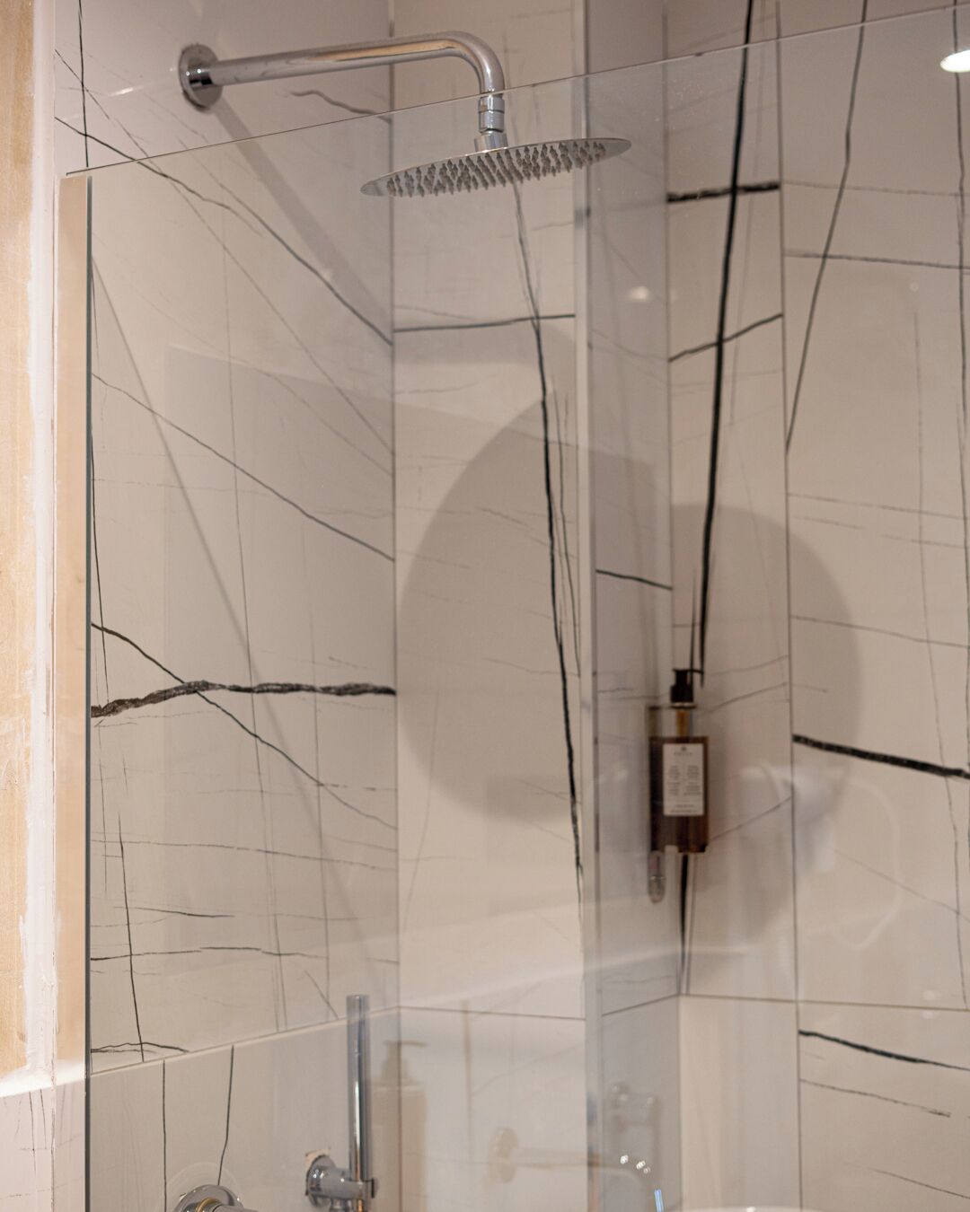 Une douche moderne dotée d’un pommeau de douche à main et d’un panneau de commande fixé au mur.