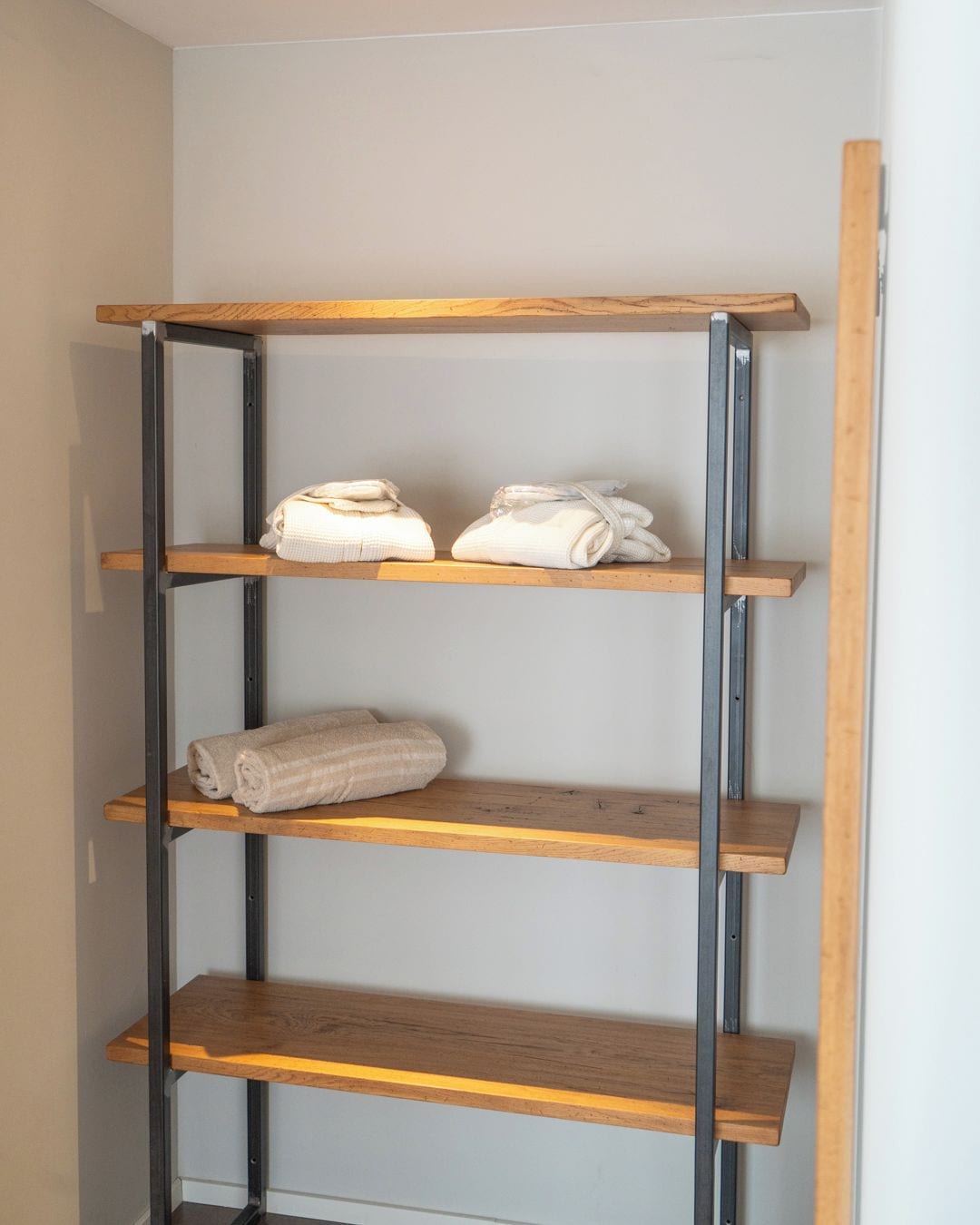 A metal and wood shelving unit with towels.