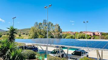 Une installation de panneaux solaires avec des voitures garées et un ciel dégagé.