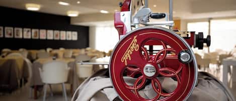 A vintage red and gold rotary meat slicer in a restaurant setting.