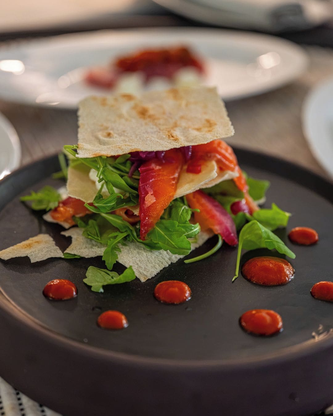 Une assiette avec un sandwich, de la salade et de la sauce.