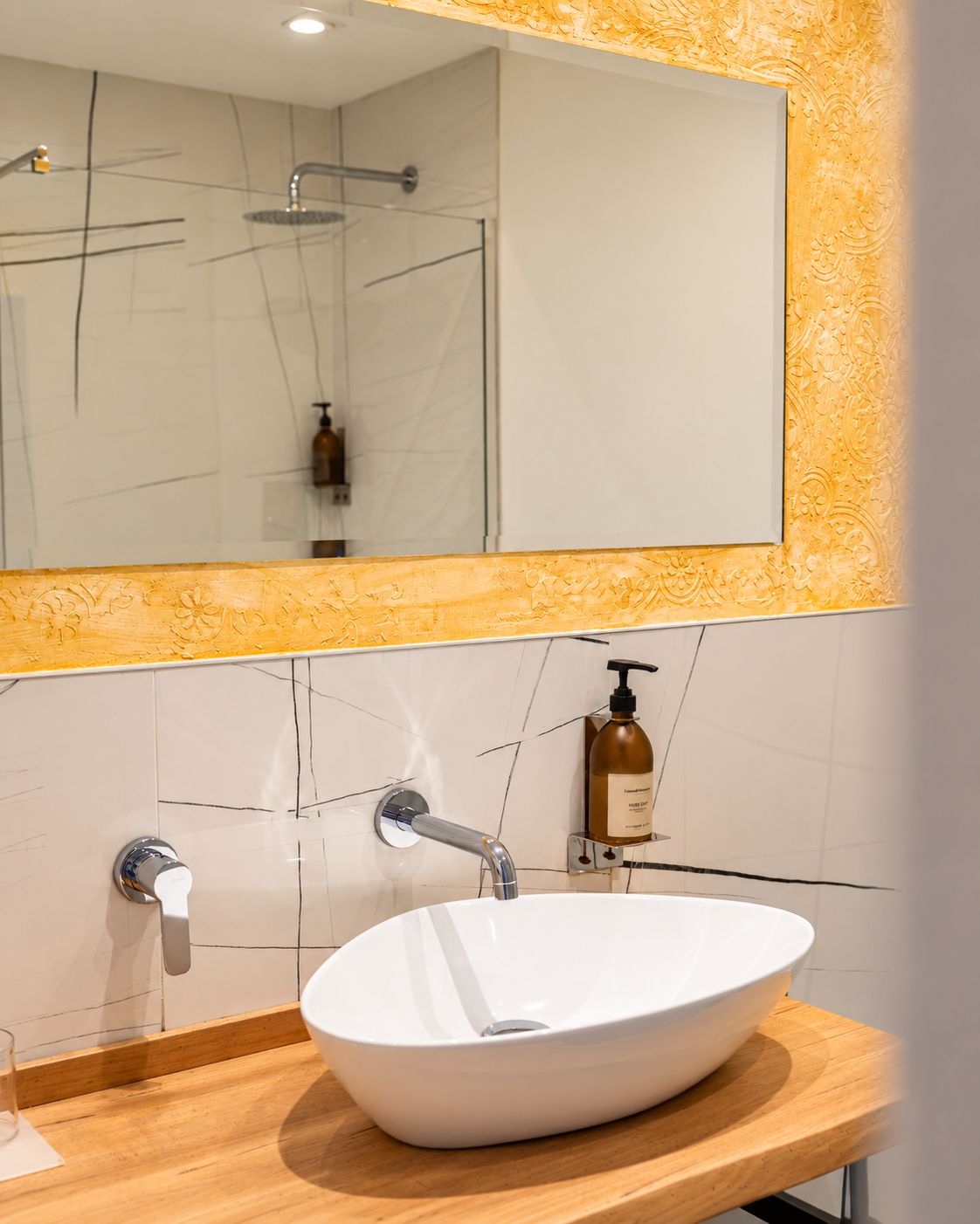 Un baño con lavamanos blanco, espejo y ducha.