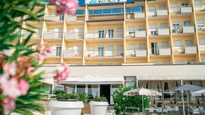 A multi-story hotel with balconies, outdoor seating, and a sign reading "ASTOR". - Hotel Astor (Jesolo)