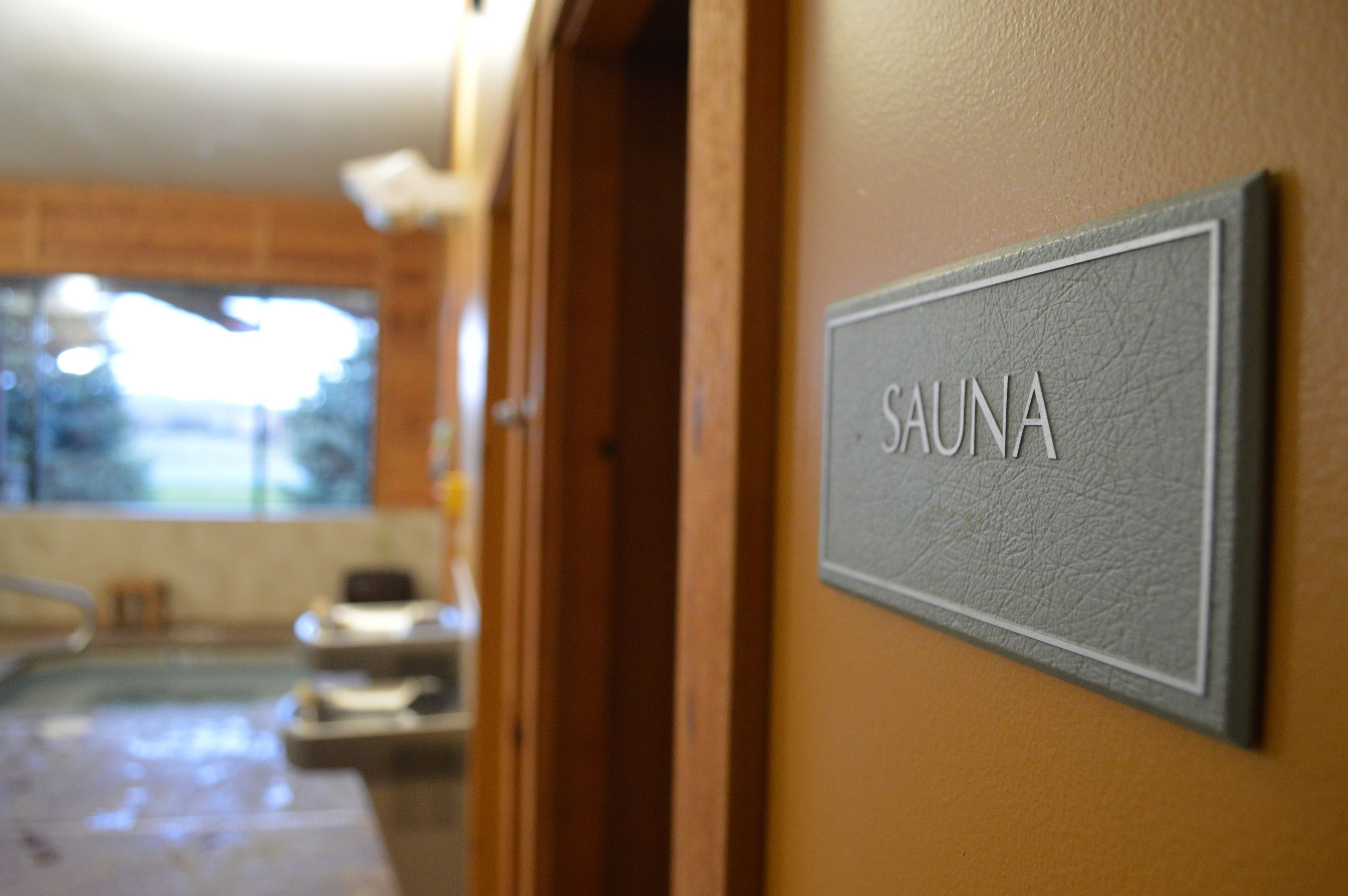 Un panneau indiquant « SAUNA » est affiché sur un mur, signalant la présence d’un espace sauna.