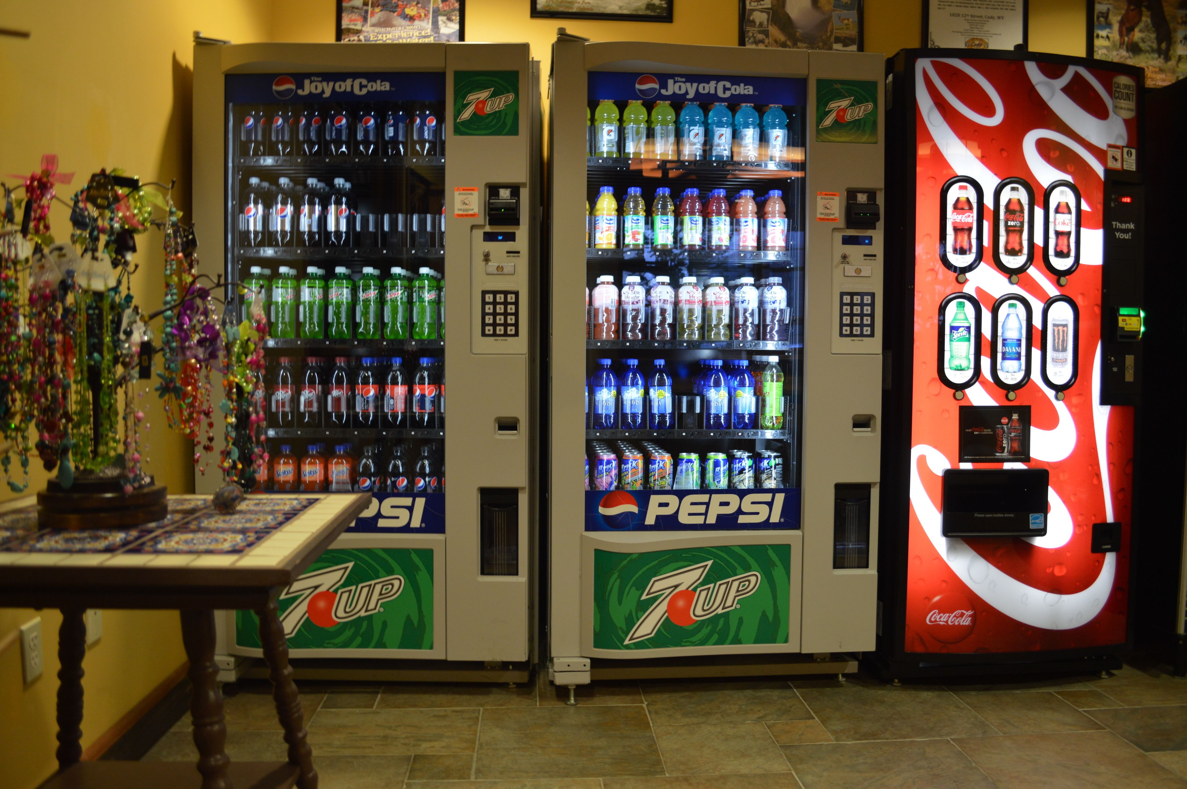Three beverage vending machines with 7UP, Pepsi, and Coca-Cola logos.