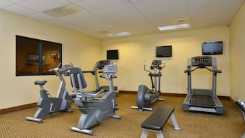 A fitness center with treadmills, elliptical machines, and a bench.