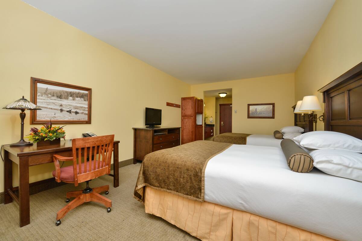 A hotel room with a bed, desk, chair, and a television.
