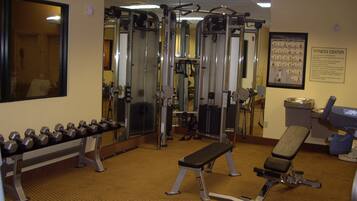 Un gimnasio con equipo de ejercicio, una banca y mancuernas.