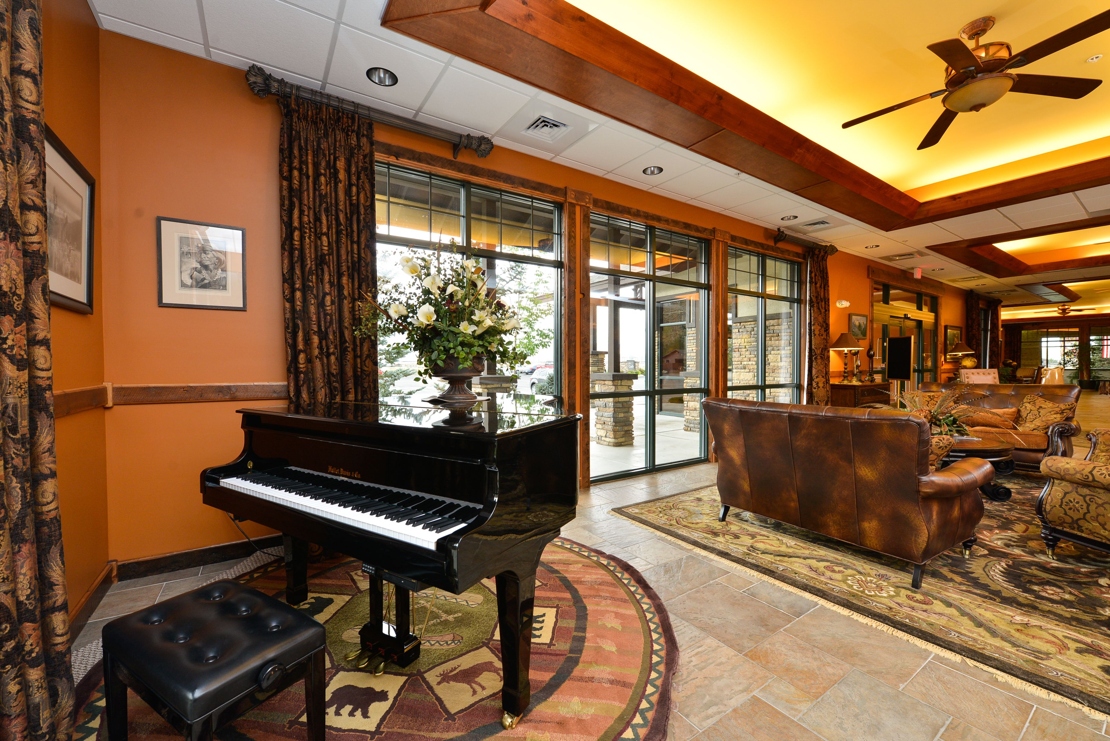 A grand lobby with a grand piano, a sofa, and a large window with curtains.