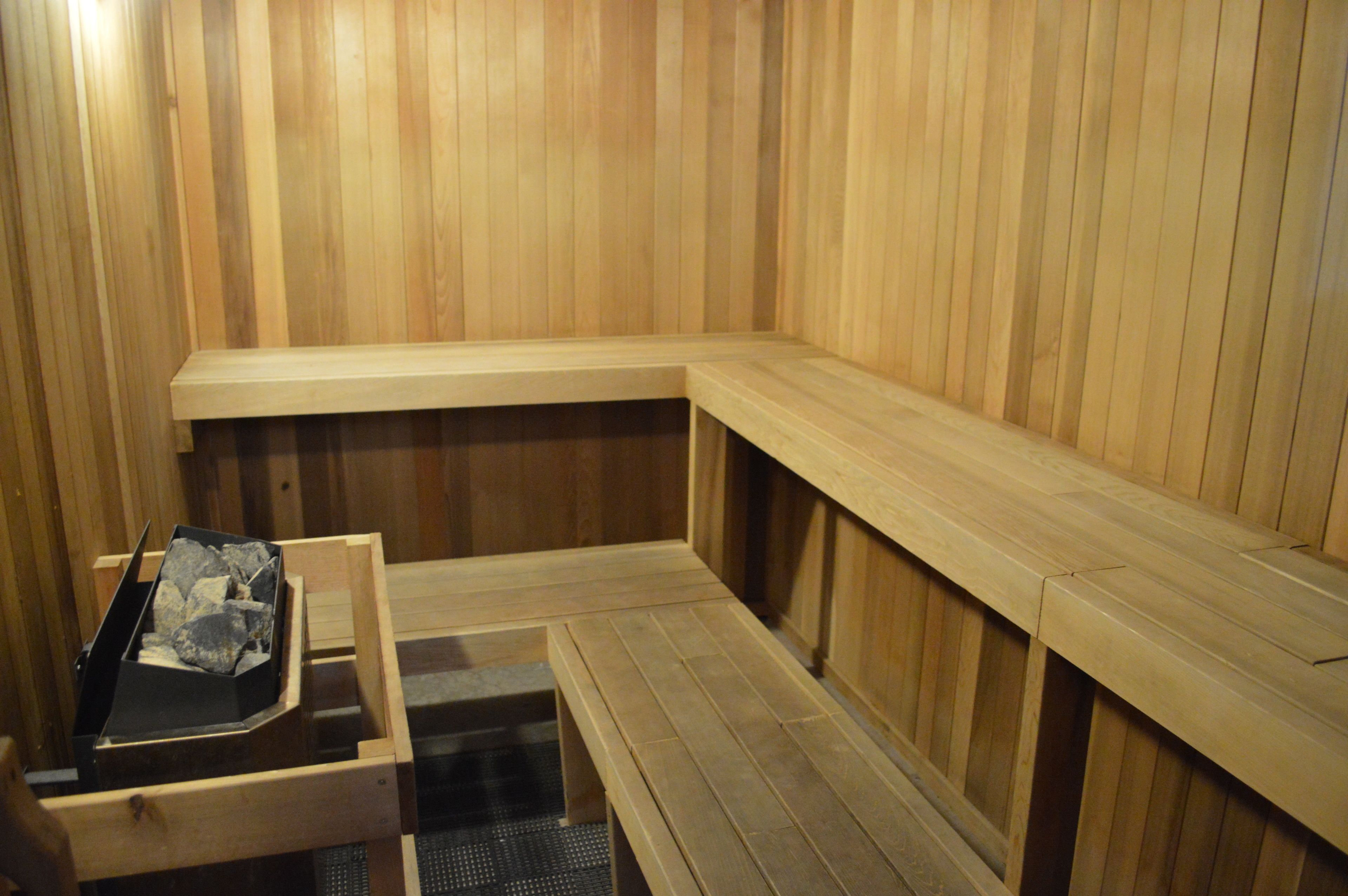 Una sauna de madera con bancos y un banco con una bandeja que contiene piedras.