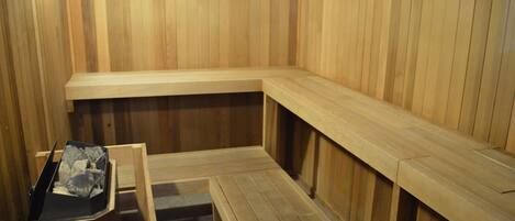 Una sauna de madera con bancos y un banco con una bandeja que contiene piedras.