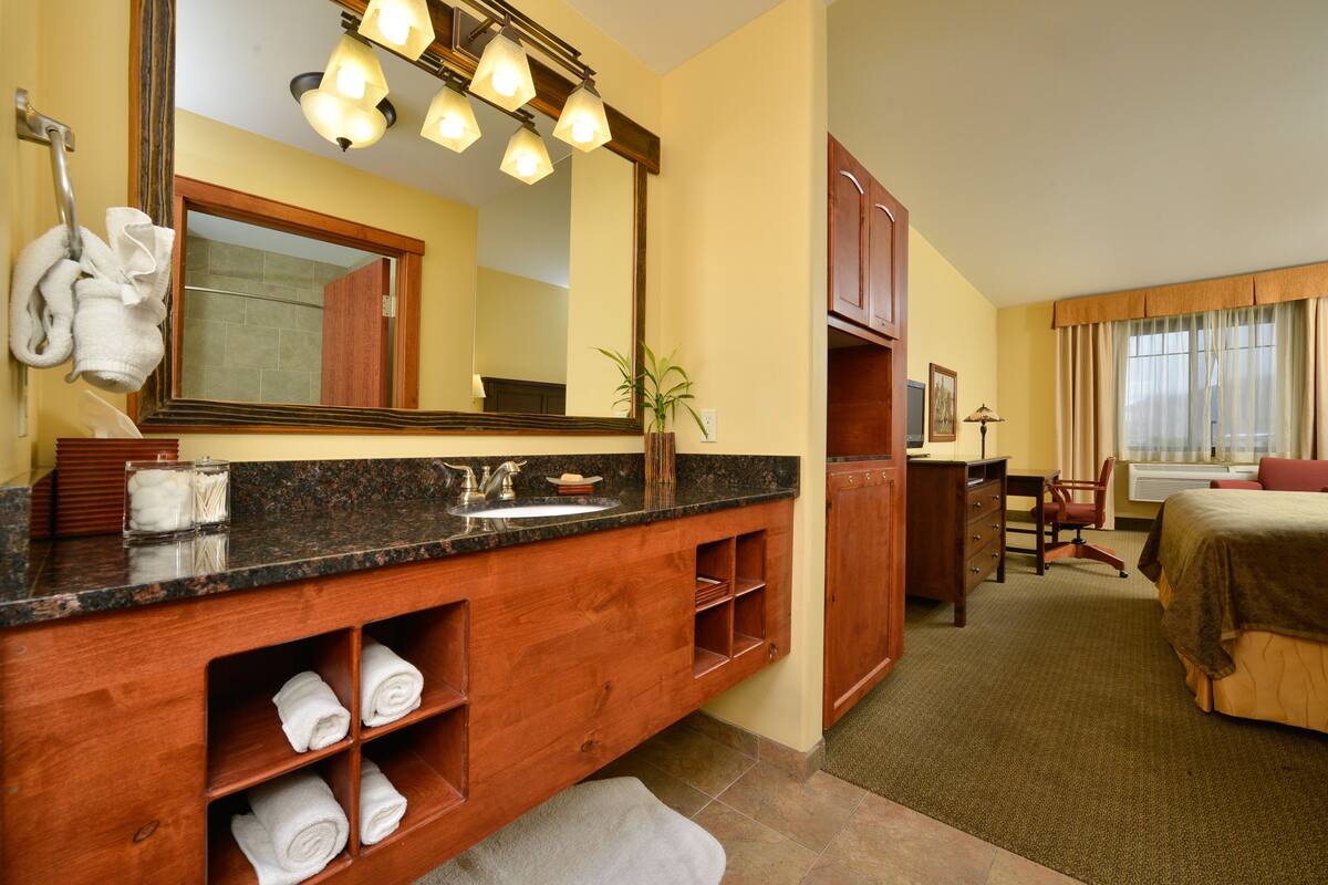 A hotel bathroom with a wooden vanity, a large mirror, and a sink.