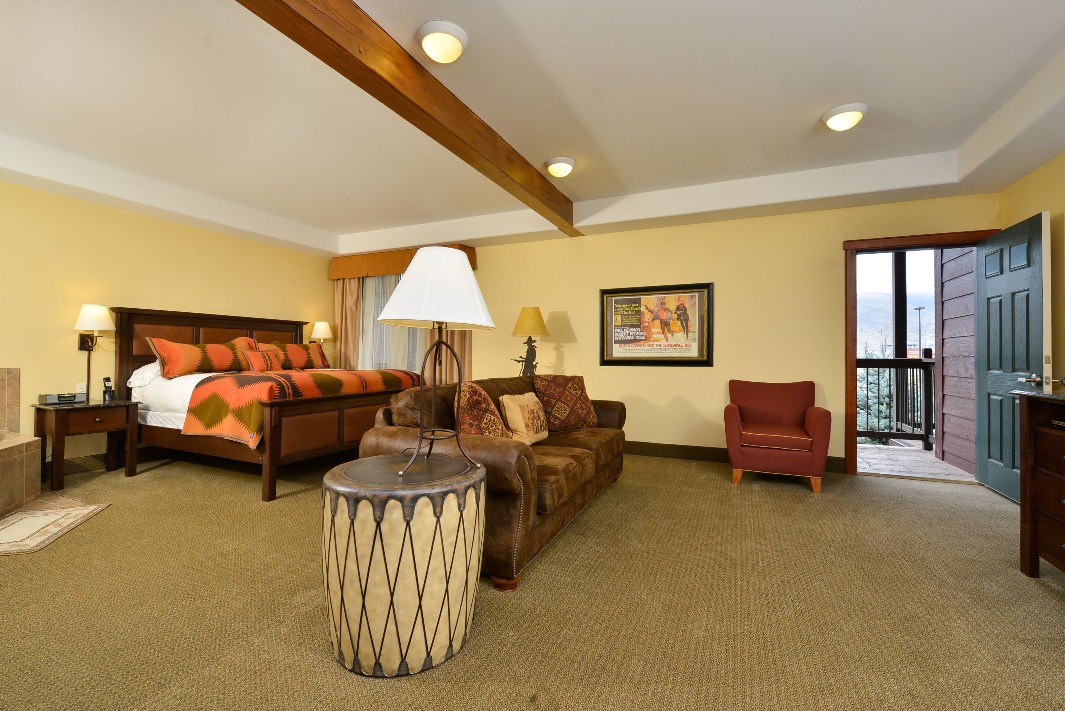 A hotel room with a bed, a sofa, a chair, a lamp, and a picture on the wall.