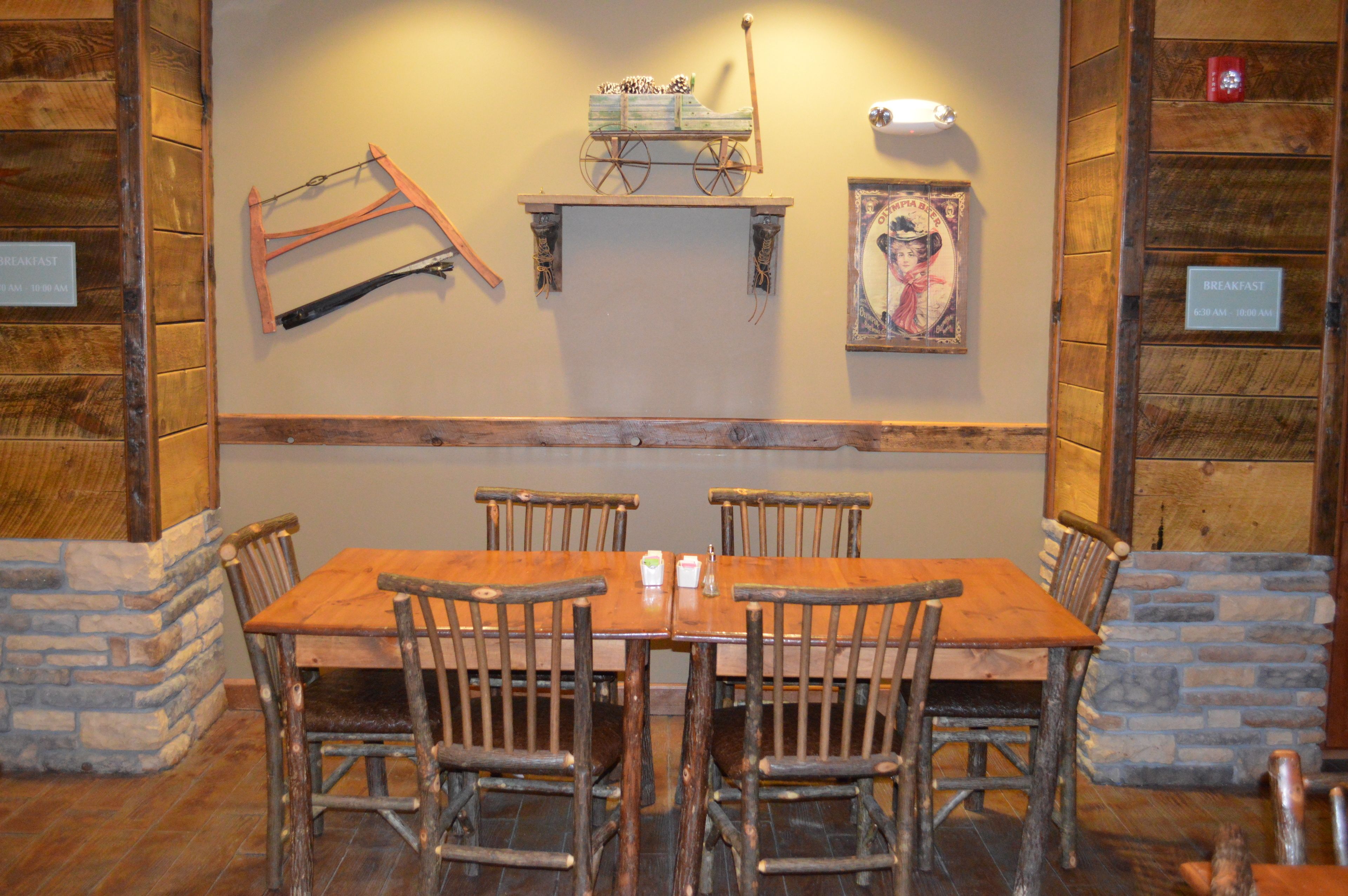 A rustic dining area with a wooden table and chairs, surrounded by stone walls and wooden paneling.