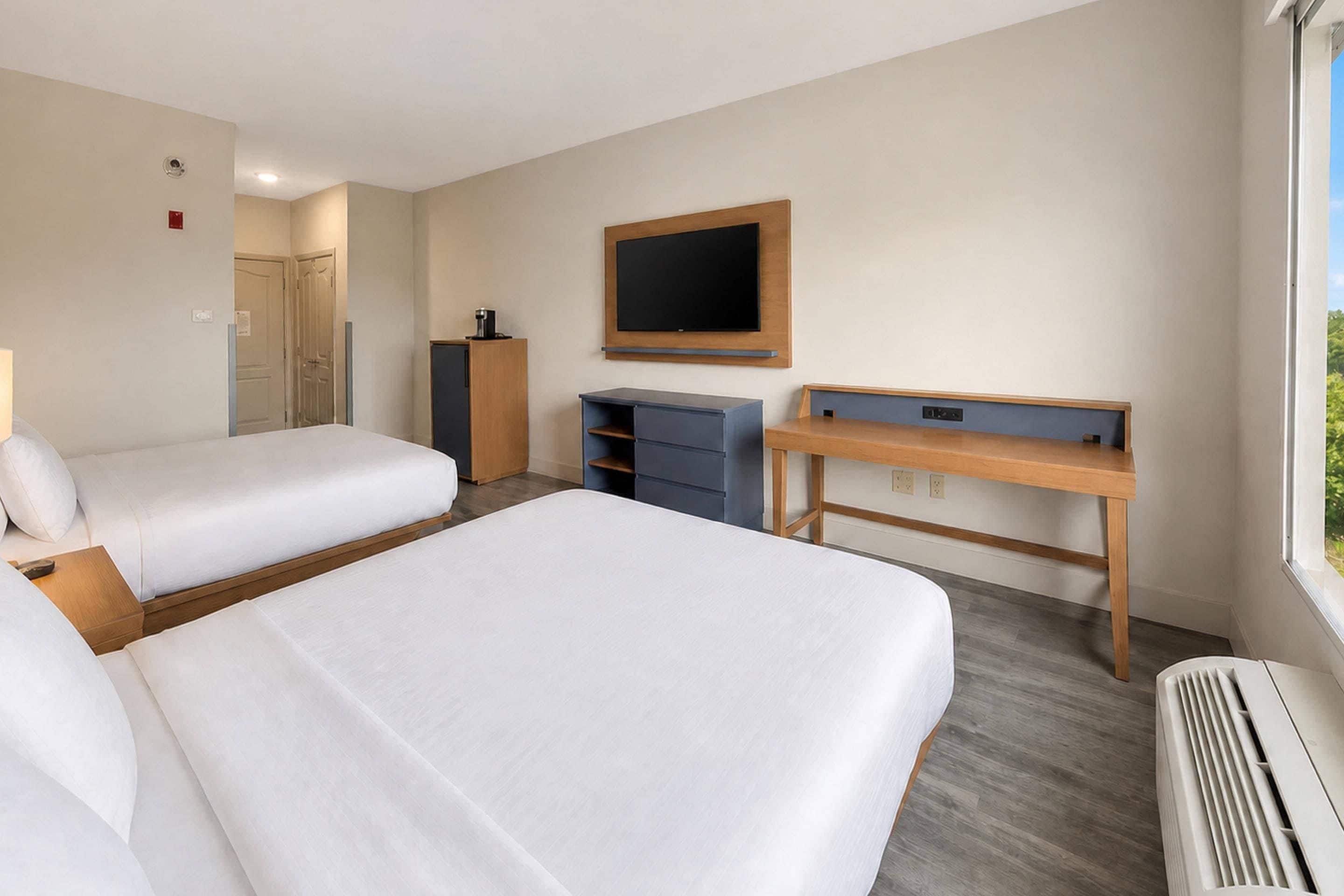Ett hotellrum med två sängar, ett skrivbord, en tv och ett fönster.