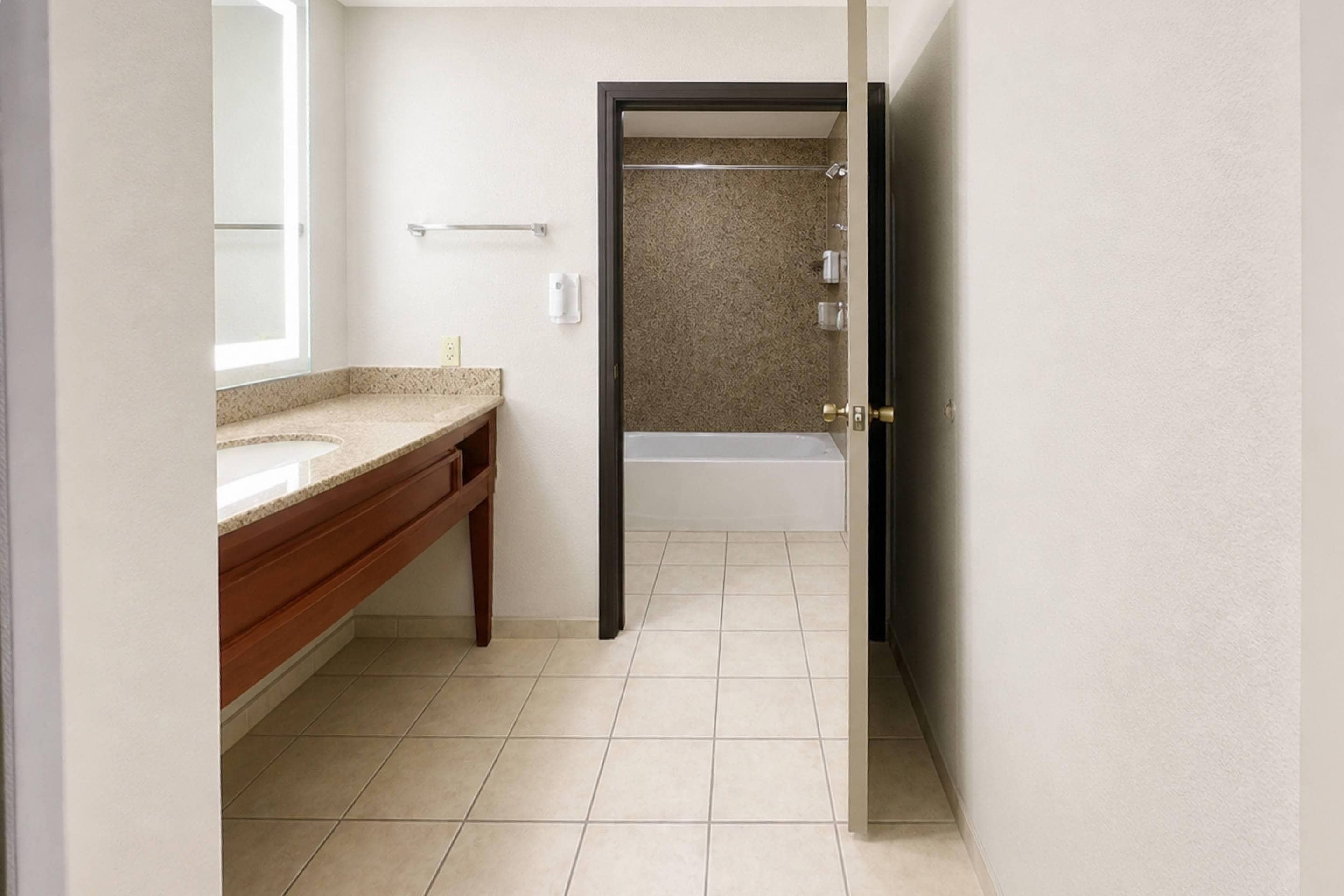 A bathroom with a sink, mirror, and a shower area.