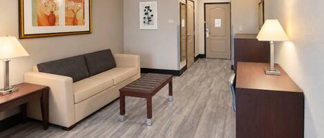A hotel lobby with a sofa, a coffee table, a desk, and a reception area.