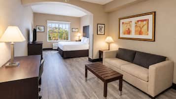 Une chambre d’hôtel comprenant un lit, un canapé, une table basse, un bureau et un téléviseur.