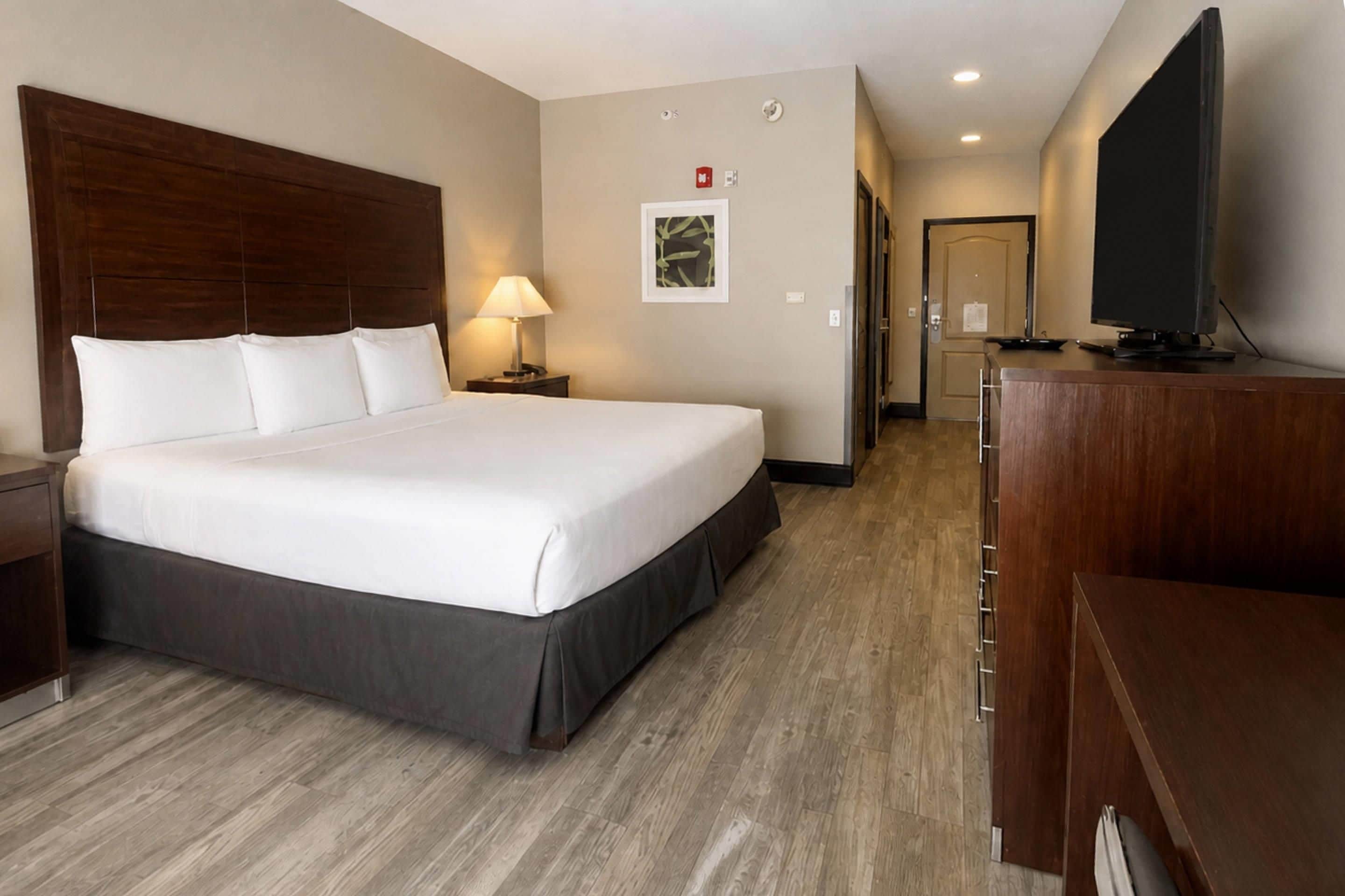 Habitación de hotel con una cama grande, un escritorio, un televisor y un pasillo que da a otras habitaciones.