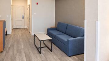 A hallway with a blue sofa, a small table, and a door with a light switch.
