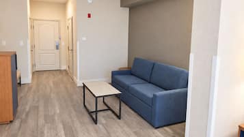 A modern living room with a blue sofa, a small table, and a wooden cabinet.