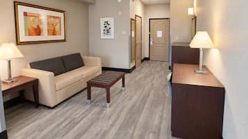 A hotel lobby with a sofa, a coffee table, a desk, and a reception area.