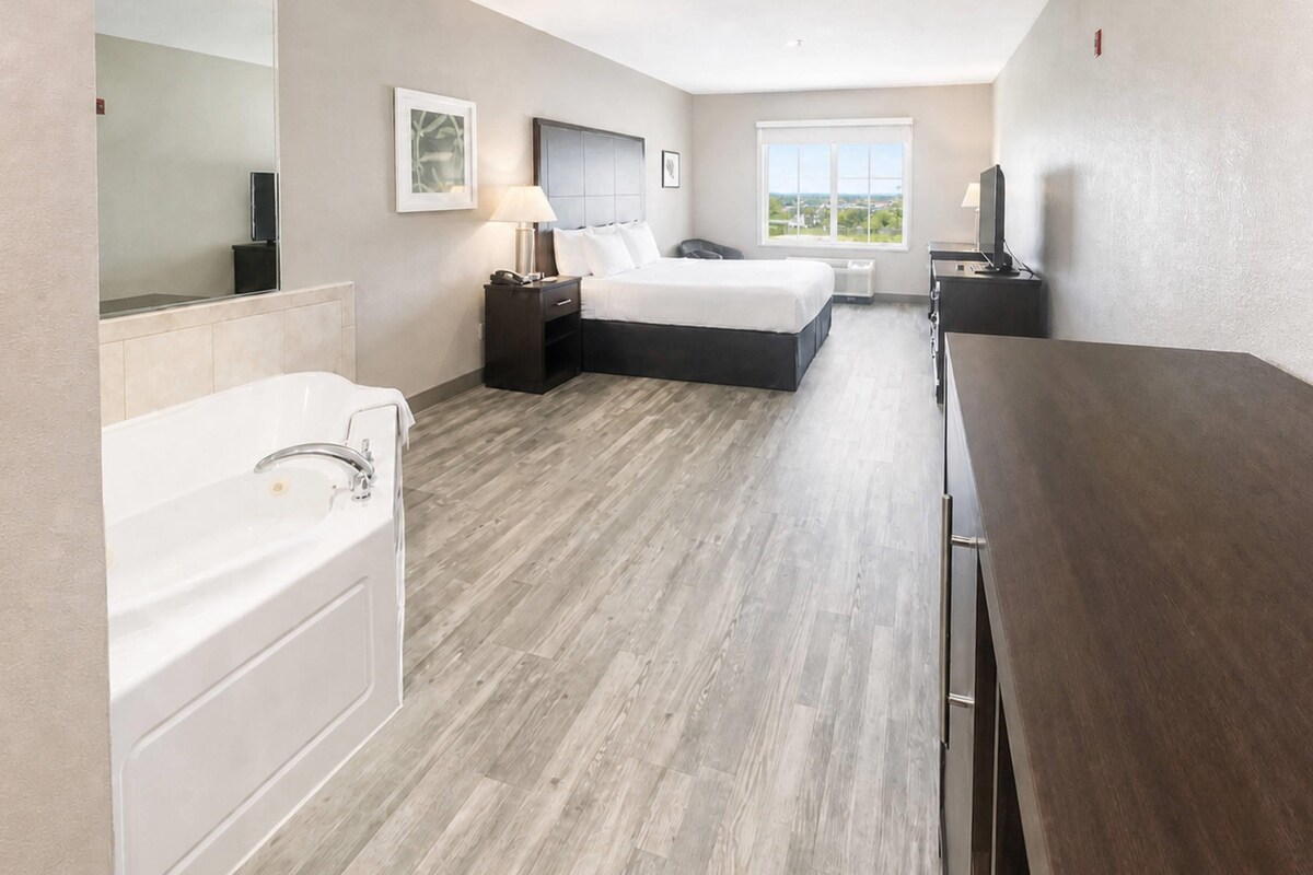 Een hotelkamer met een bed, een bureau, een stoel, een wastafel en een raam met uitzicht.