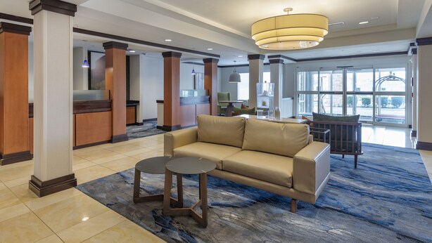 A lobby with a beige sofa, two round tables, and a blue patterned carpet. - Country Inn & Suites by Radisson, Pensacola West, FL (Pensacola)