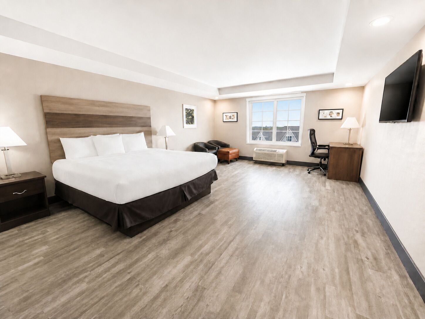 A hotel room with a large bed, a desk, a chair, a TV, and a window with a view.